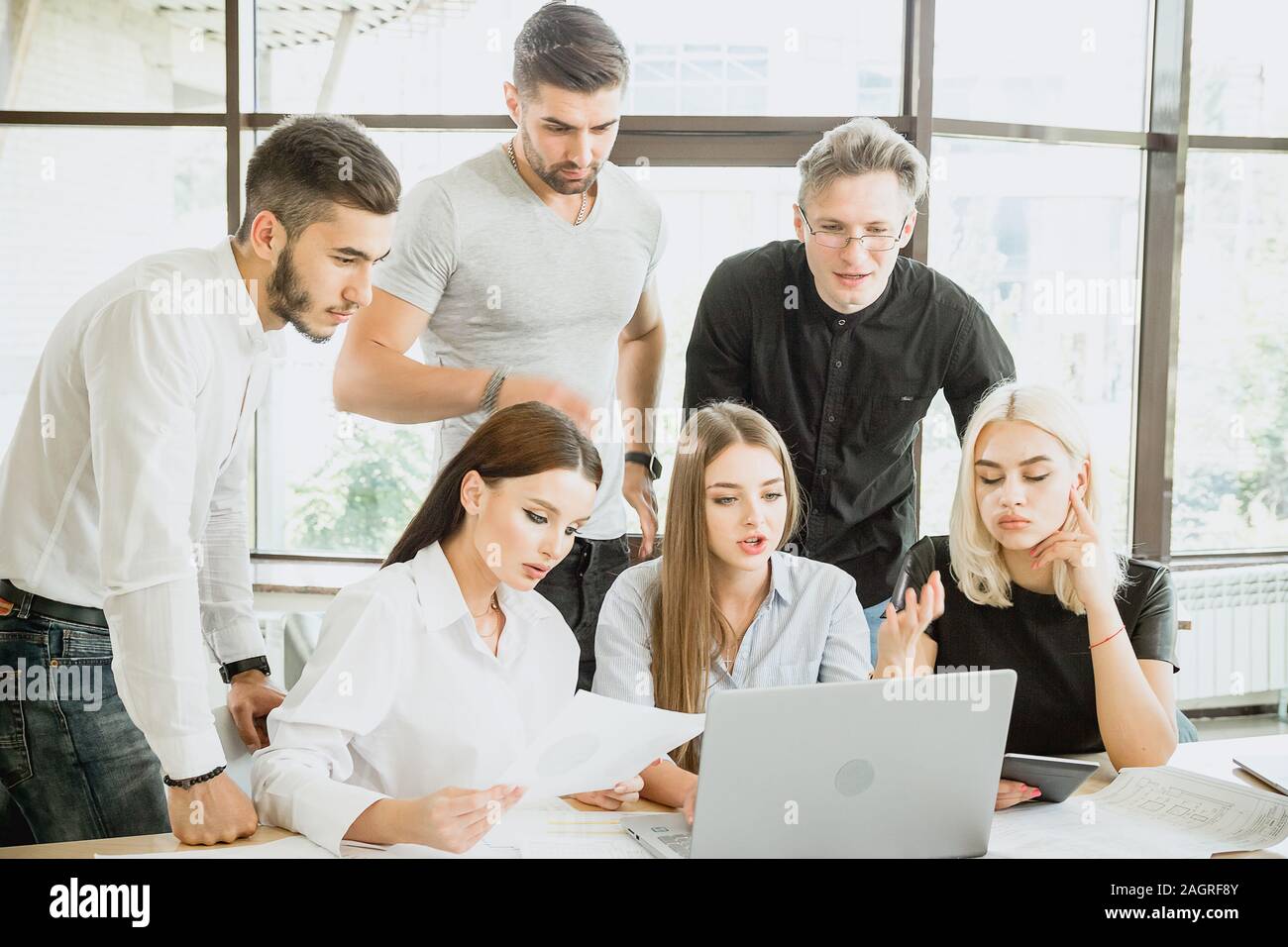 Team of young people in work process in front of laptop Stock Photo