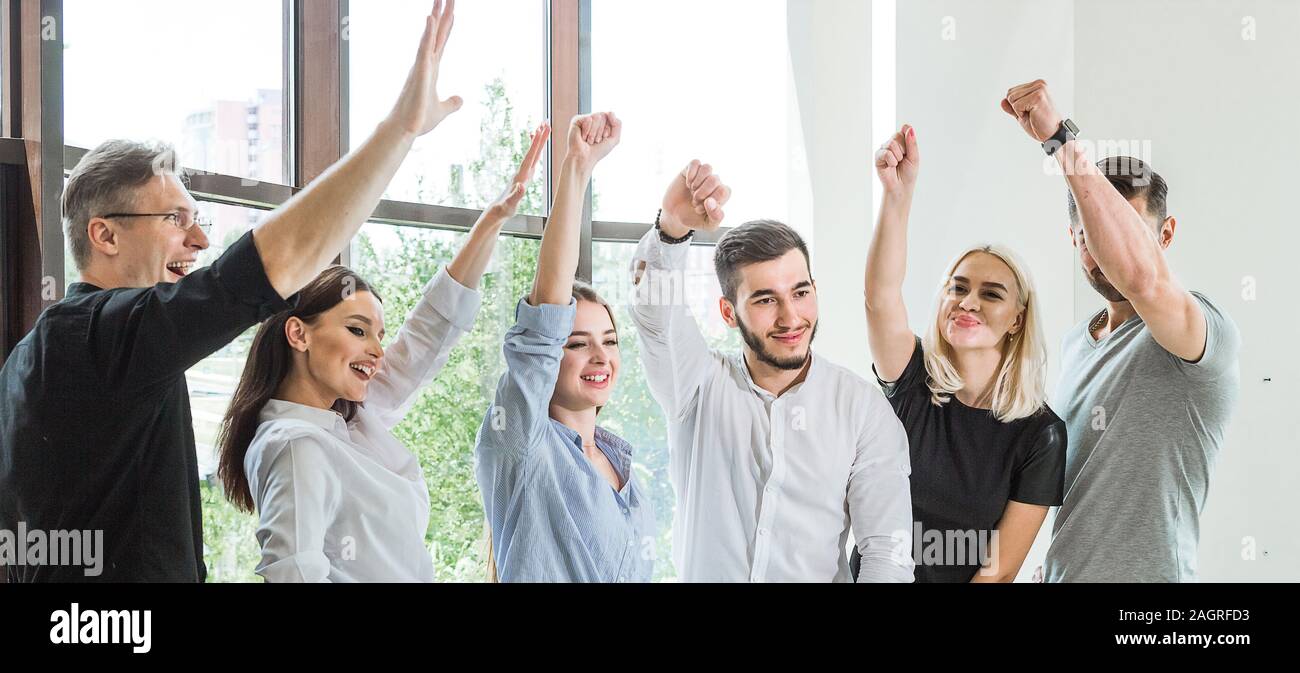 The outcome of the meeting. A company of young people raises their fists up. Laughter and smiles on faces Stock Photo