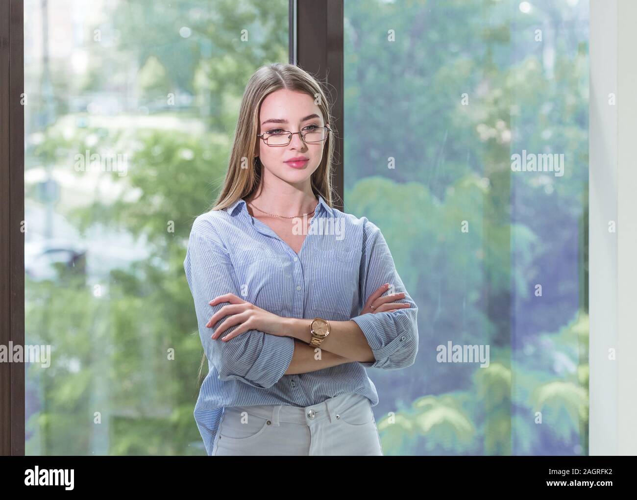 Thoughtful young lady with glasses in blue shirt is thinking about and dreaming. She crosses her arms over chest. Occupation concept Stock Photo