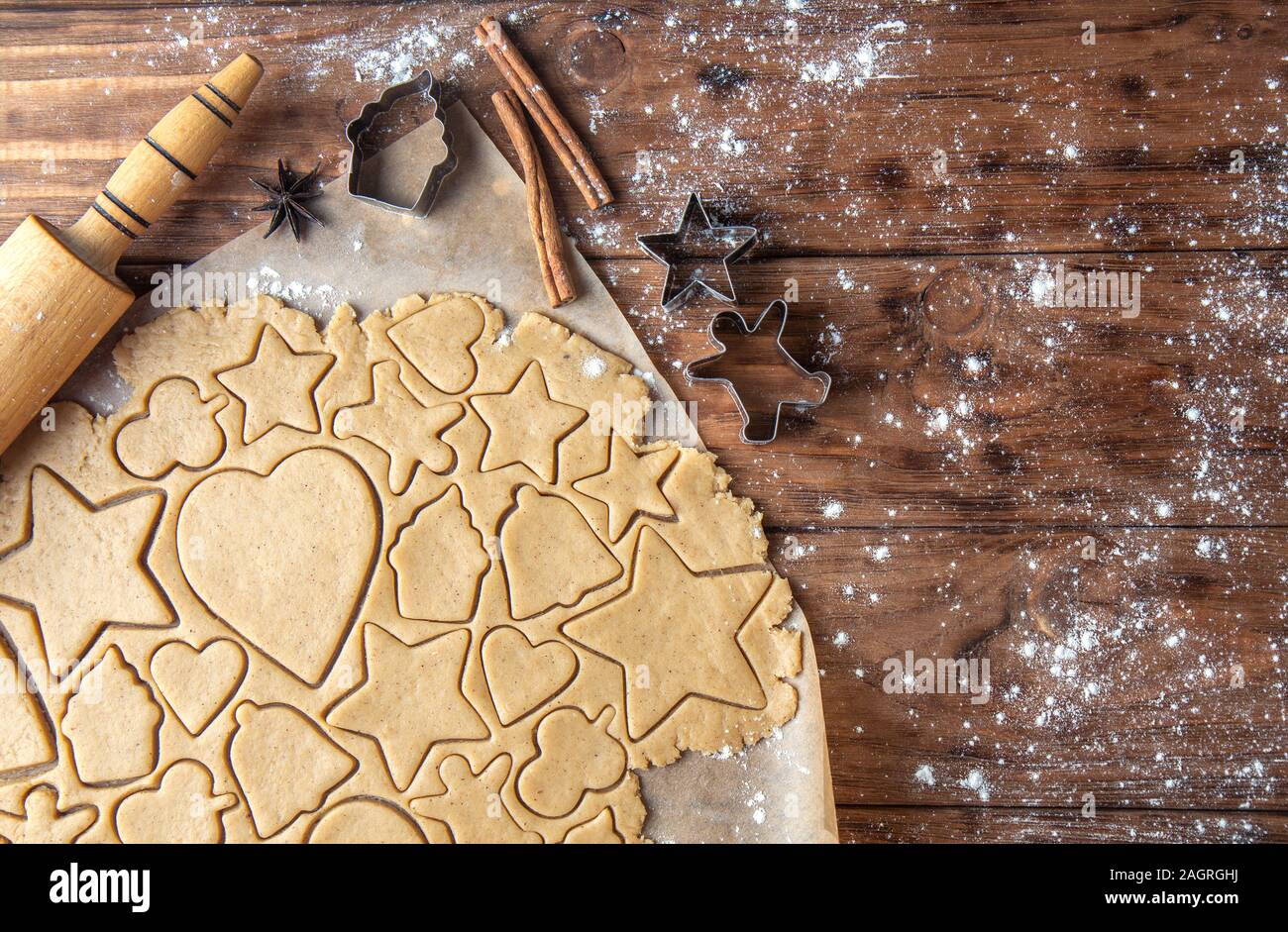 Cutting ginger biscuits in different shapes on a wooden background ...