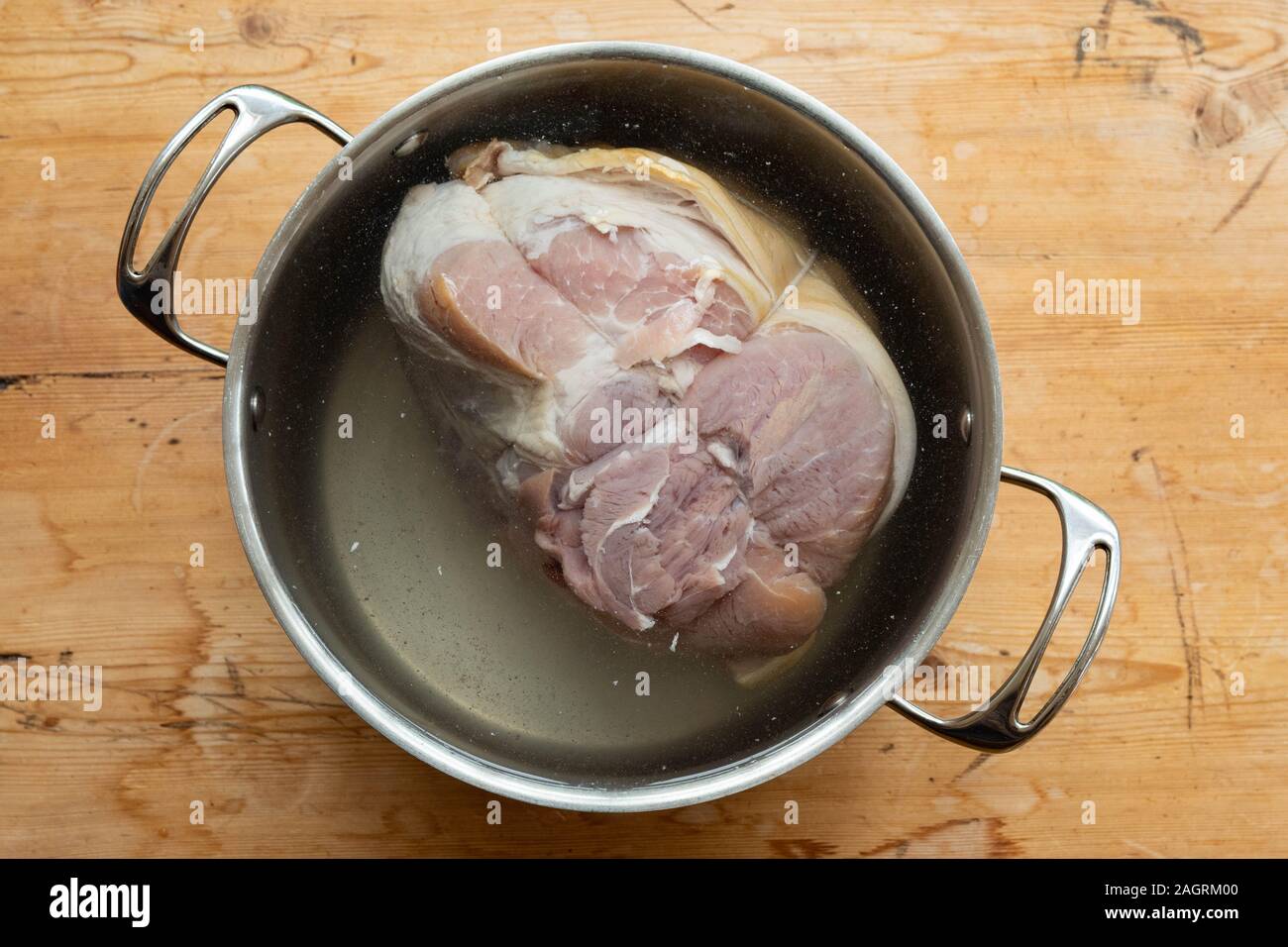 Soaking a ham joint in water to remove salt before cooking Stock Photo