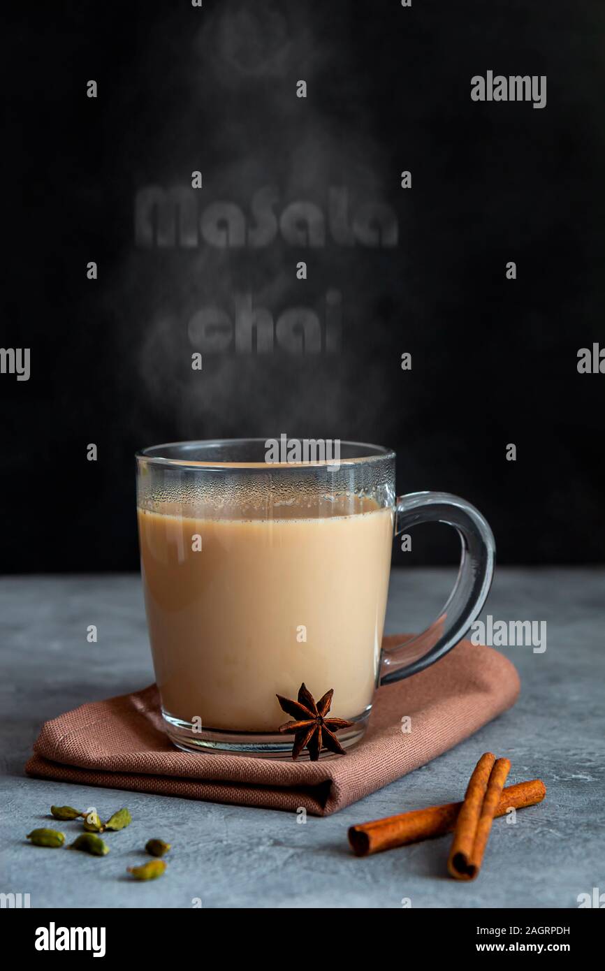 Indian tea masala chai with spices in a glass mug on a dark background. Vertical orientation, copy space Stock Photo