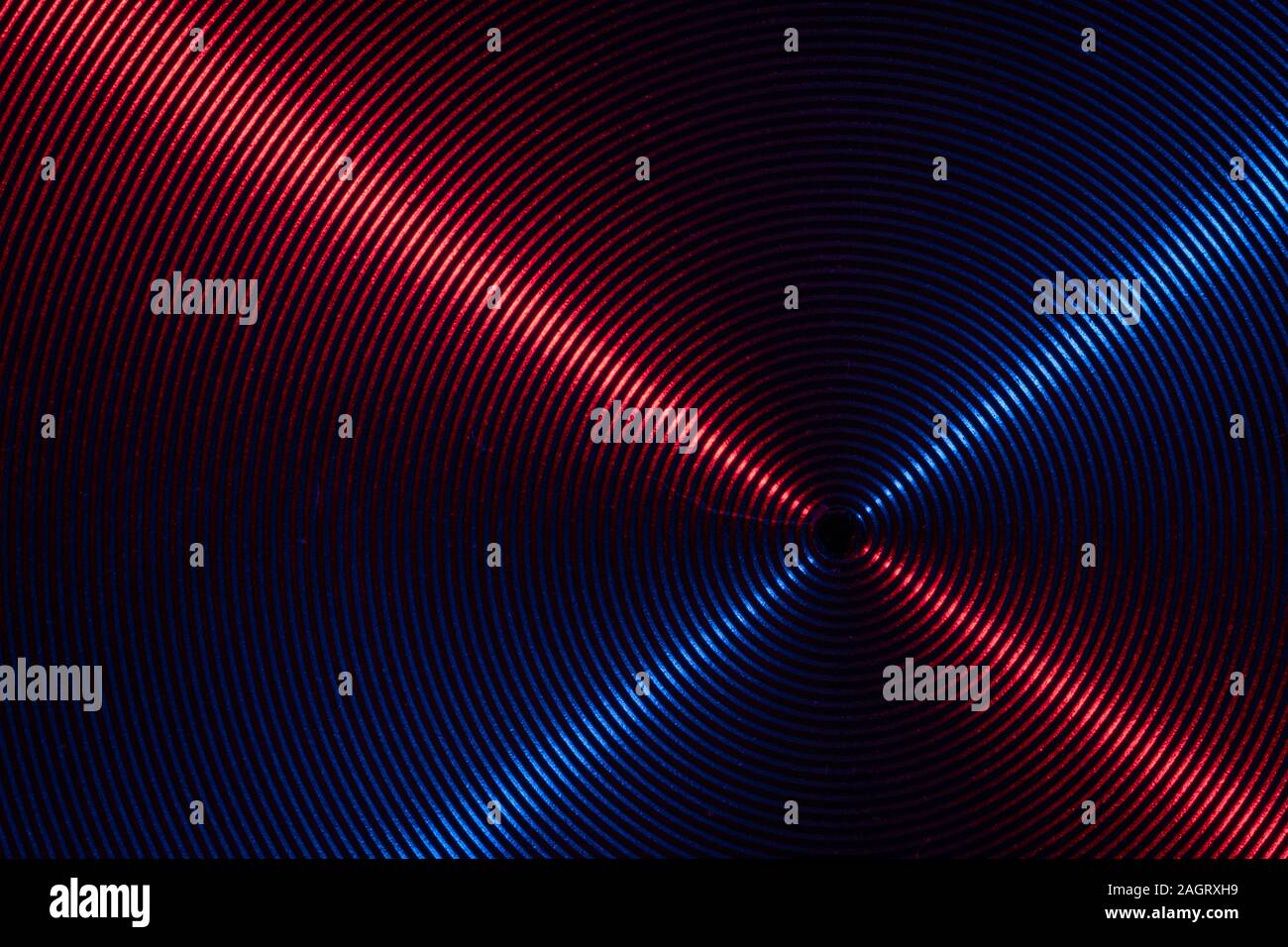 A close up macro photo of circular brushed steel metal texture with crossed red and blue lines Stock Photo