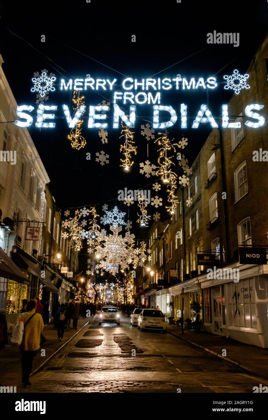 Christmas Lights above the street saying Merry Christmas from Seven Dials with snowflake decorations in background, evening, Central London. Stock Photo
