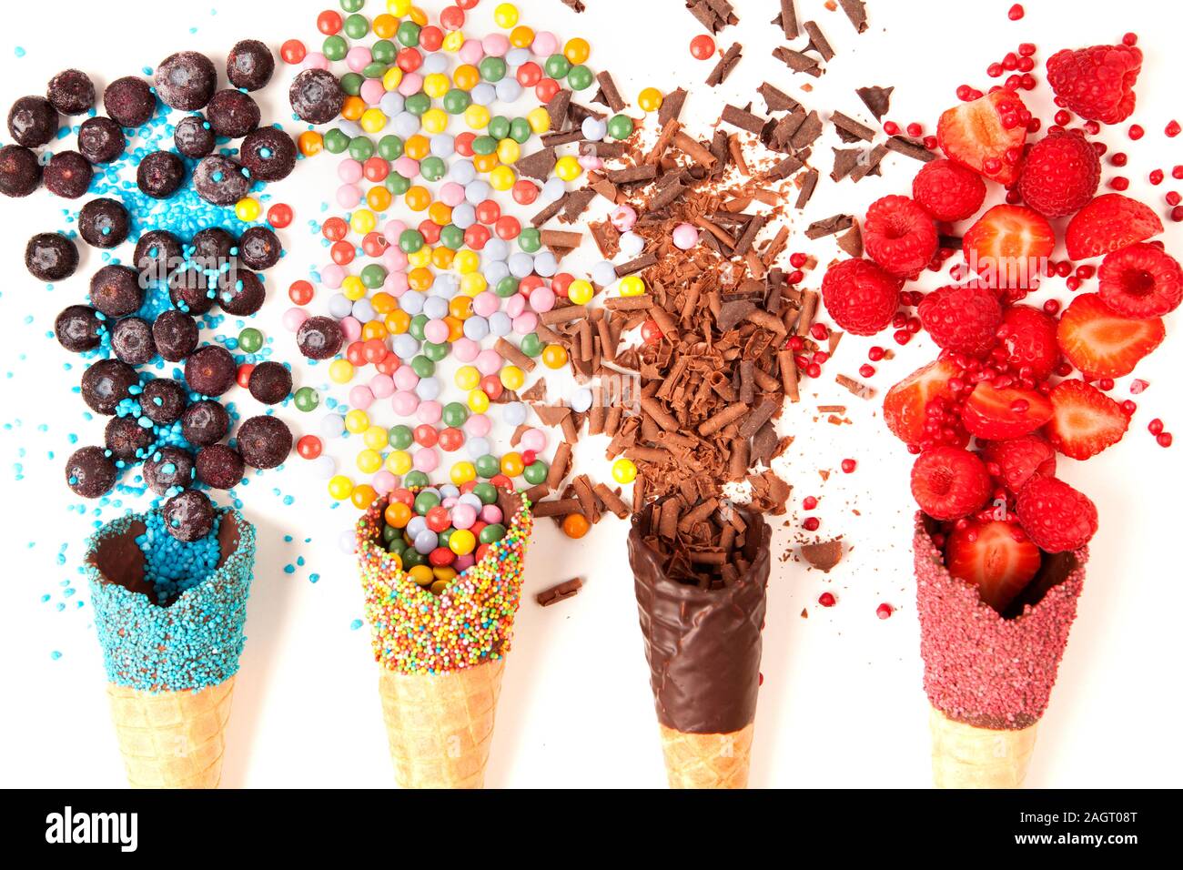 Ice cream cones with colourful toppings and fruit on white flat lay Stock Photo