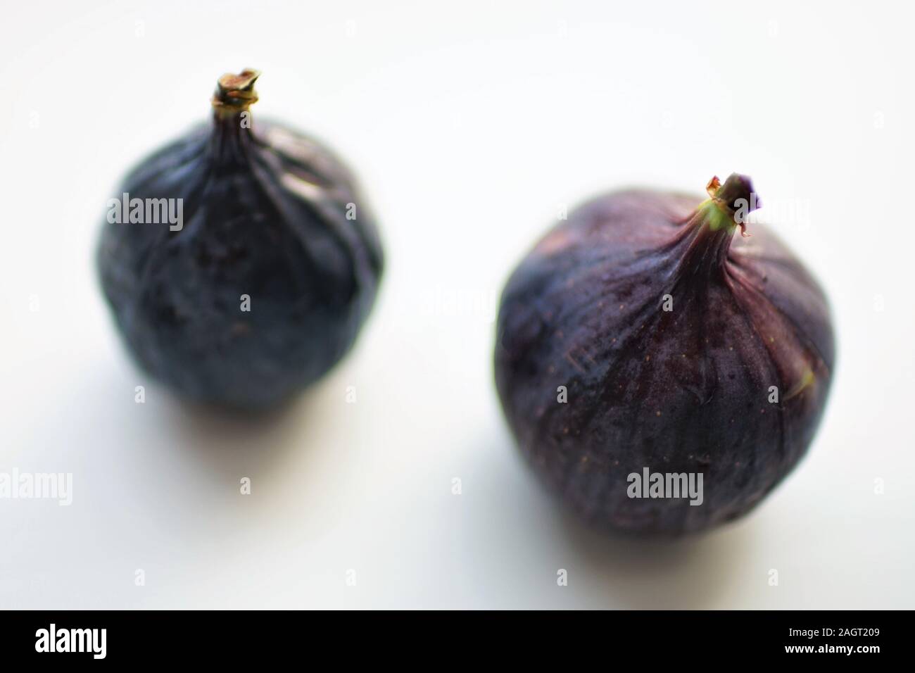 Two ripe sweet figs on white table. Selective soft focus. Stock Photo
