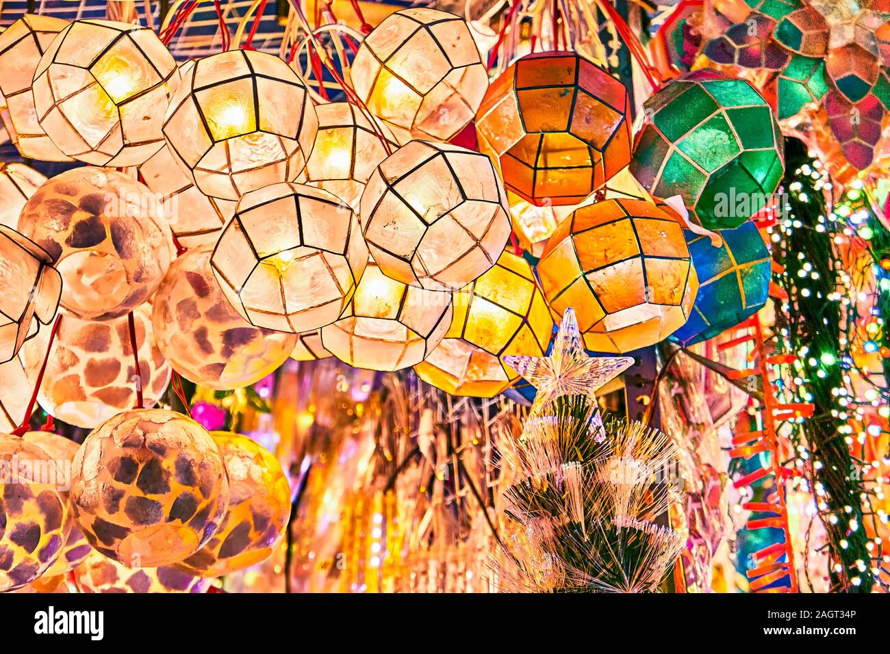 Brightly illuminated colorful traditional lanterns made of thin sea shells hanging outside a shop at Divisoria market in Manila, Philippines. Stock Photo