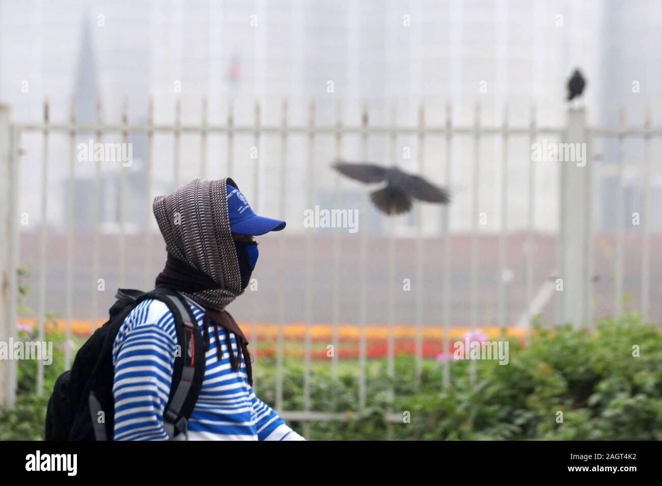 Dhaka, Bangladesh. 22nd Dec, 2019. A man walks past the parliament House during a cold wave in Dhaka.A biting cold spell continues to sweep across northern Bangladesh and a few other parts of the country although mercury readings point to an end to a cold wave. Credit: Sultan Mahmud Mukut/SOPA Images/ZUMA Wire/Alamy Live News Stock Photo
