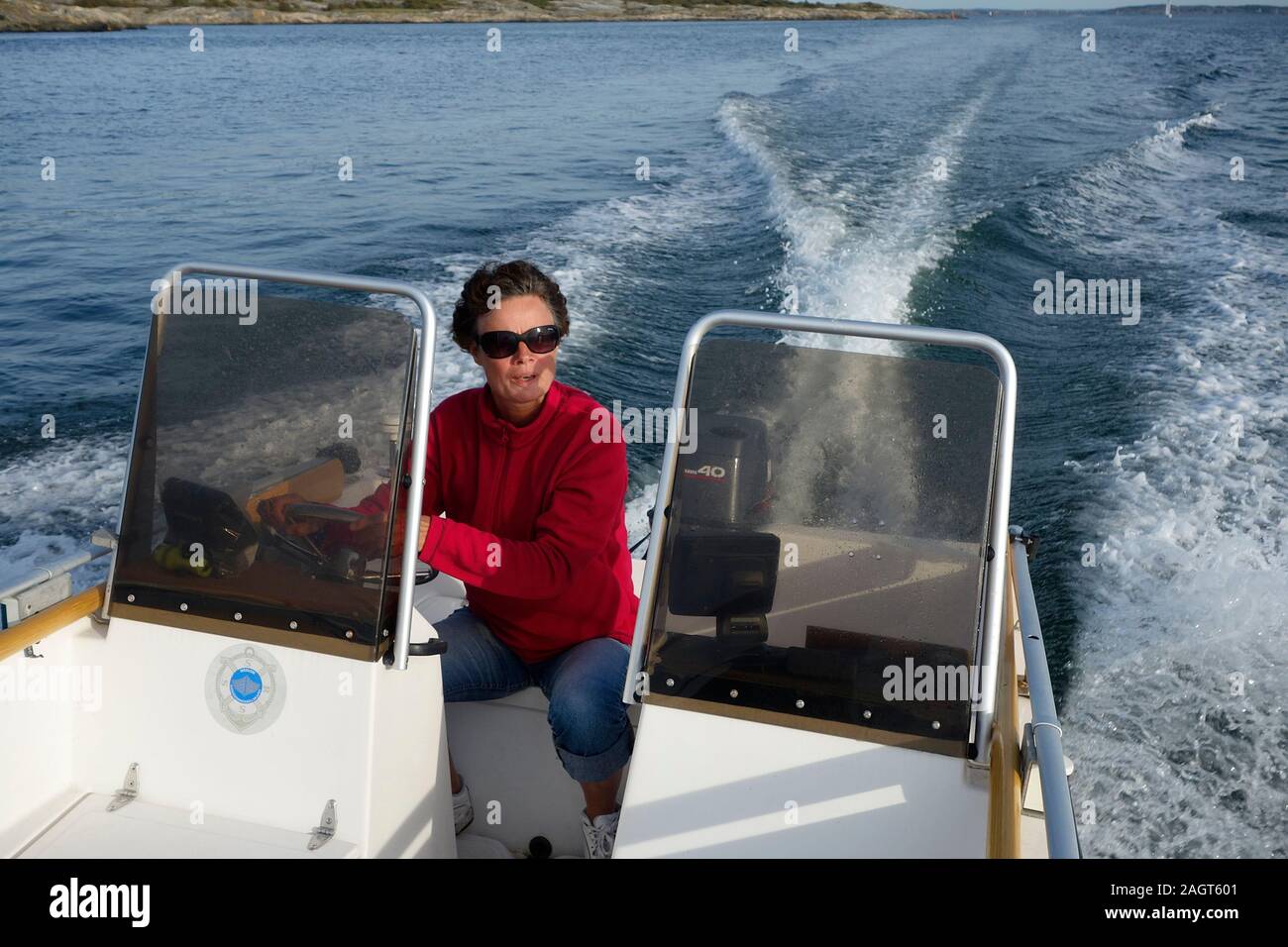 A woman steers a speed-boat on the calm sea. Stock Photo