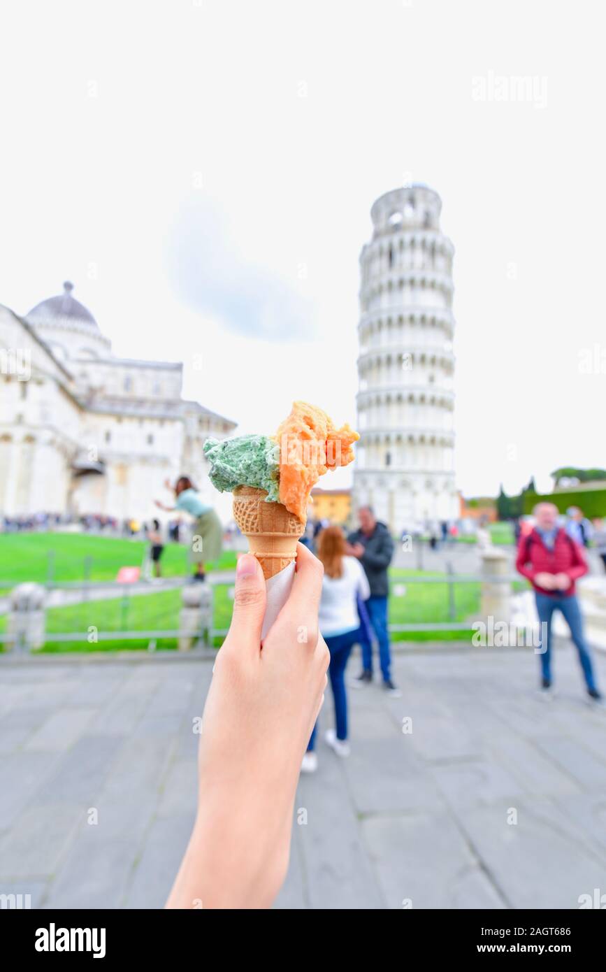 Hand Holding Gelato with the Leaning Tower of Pisa as Background Stock Photo