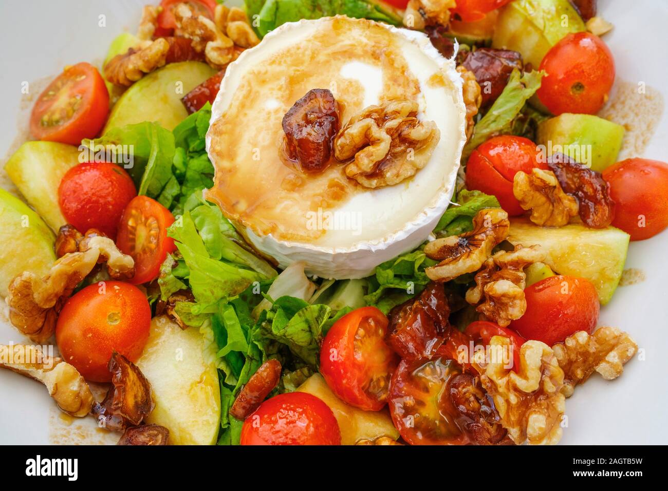 Healthy food. Goat cheese salad with tomatoes, apples, nuts and dates