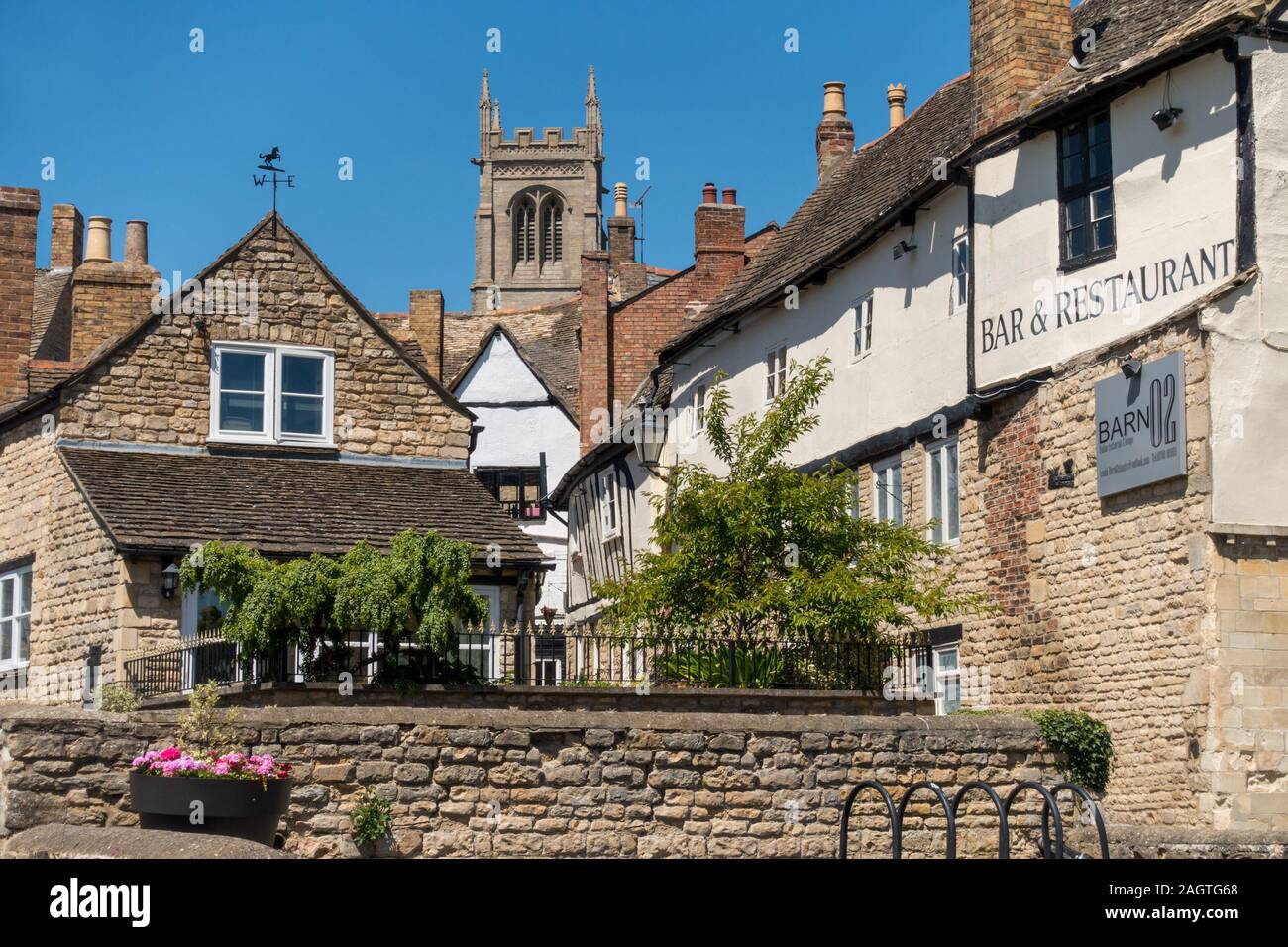 St Michaels Church tower and old stone buildings on a sunny Summer day with blue sky, Stamford, Lincolnshire, England, UK Stock Photo