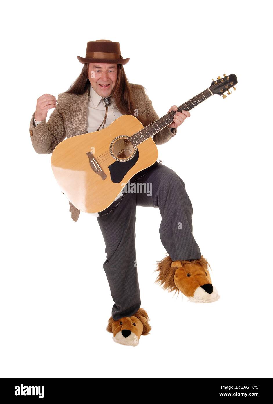 A middle age indigenous man in fancy shoes dancing and playing his guitar in a jacket and hat, isolated for white background Stock Photo