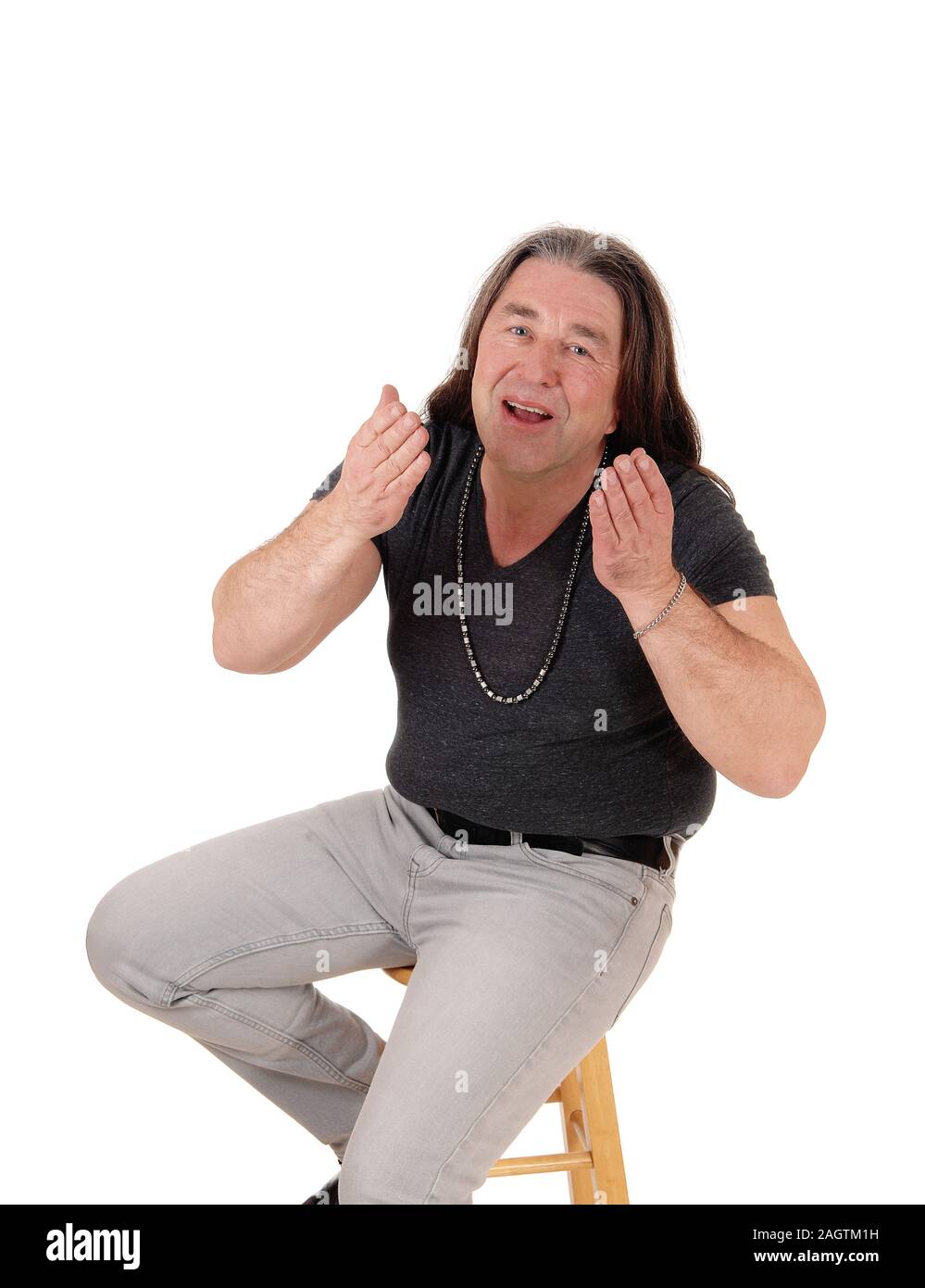 A close up image of a middle age indigenous man sitting on a chair and blowing a kiss, isolated for white background Stock Photo