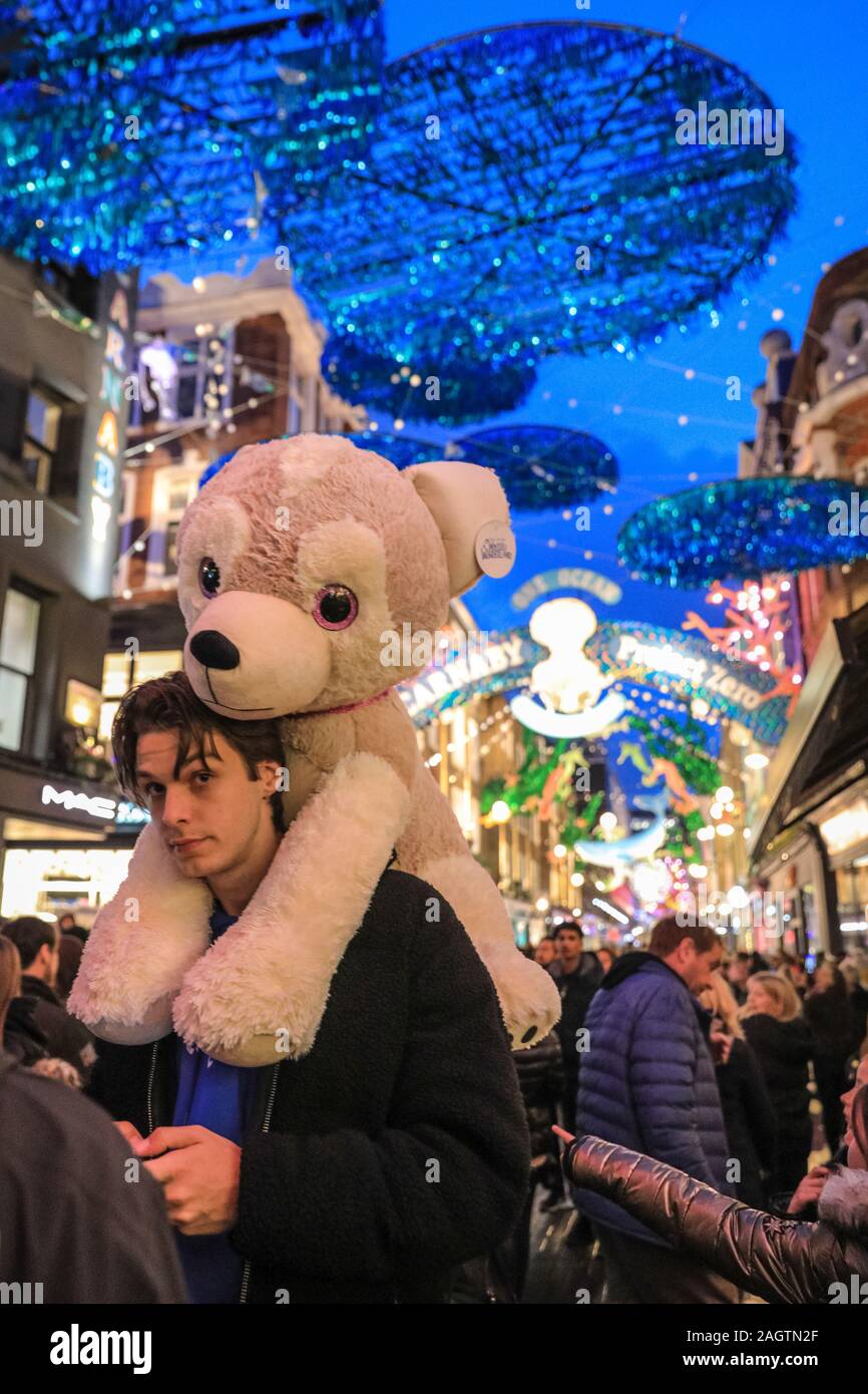 Central London, London, 21st Dec 2019. A young man carries his 'Winter Wonderland' cuddy toy price thorugh Carnaby Street, which is crowded with shoppers. Shoppers in Oxford Street, Regent Street and Bond Street rush to make their last minute purchases in time for Christmas, whilst shops have already started heavy discounting on many goods. Stock Photo