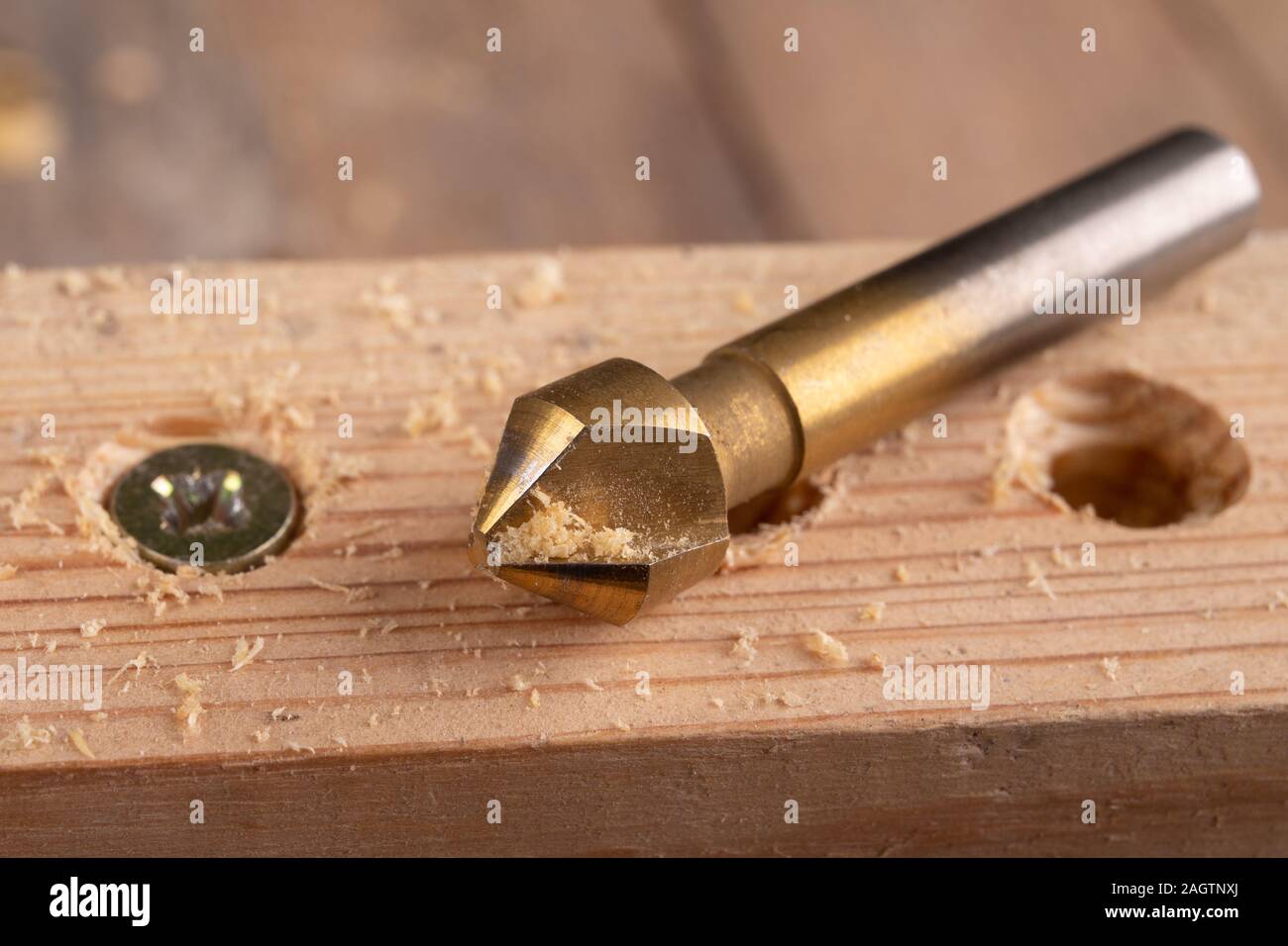 Drilling holes in a piece of wood. Countersinking the hole for wood screws. Dark background