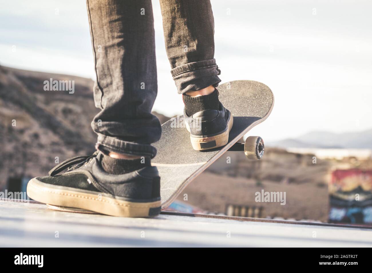 Close up view of teen's feet on a skateboard ready to start a ride over the half pipe. Skater starting jumps and tricks at the skate park. Let's go en Stock Photo