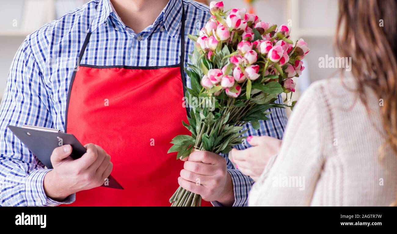 The flower shop assistant selling flowers to female customer Stock