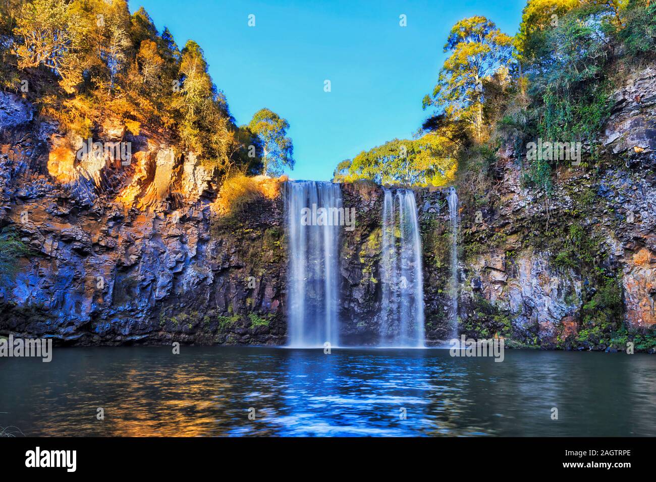 Scenic section of lower Dangar falls falling down to fresh water pool cutting through vulcanic rocks in Dorrigo national park under clear blue sky in Stock Photo