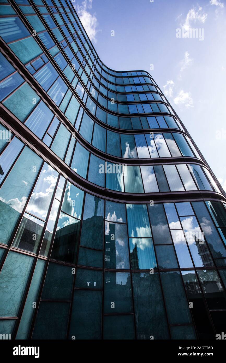 A high rise building in a glass facade with the reflection of the ...
