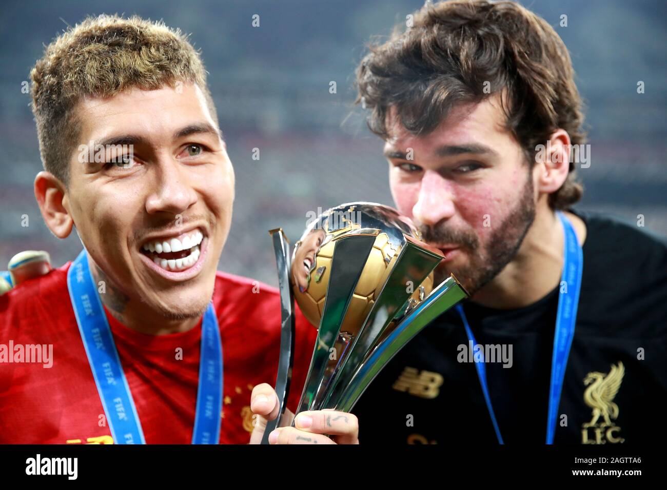 Liverpool's Roberto Firmino (left) and Alisson (right) celebrate with the trophy after the final whistle during the FIFA Club World Cup final at the Khalifa International Stadium, Doha. Stock Photo