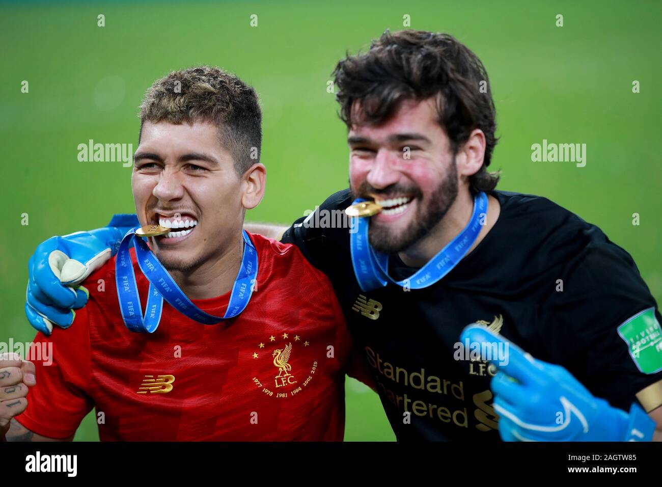 Liverpool's Roberto Firmino (left) and Alisson (right) celebrate with their medals after the FIFA Club World Cup final at the Khalifa International Stadium, Doha. Stock Photo