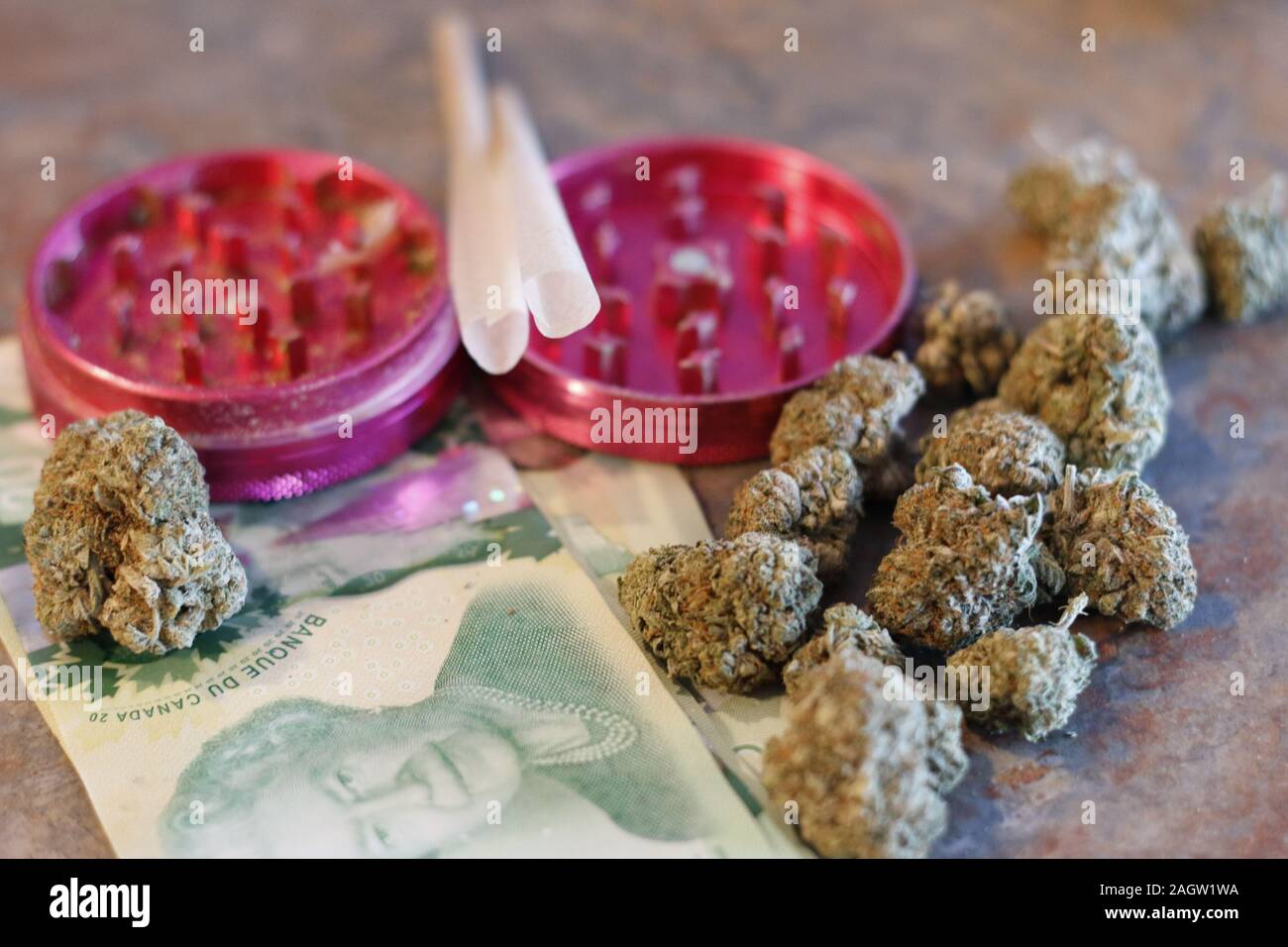 A grinder, pre rolled joints, canadian money, and weed Stock Photo Alamy