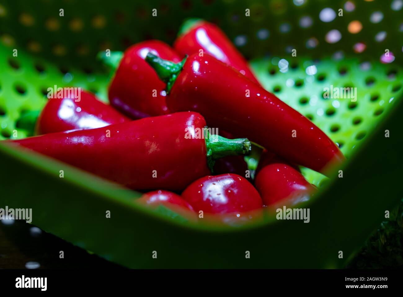 Freshly washed red spicy chilli in a green drainer ready to cook Stock Photo