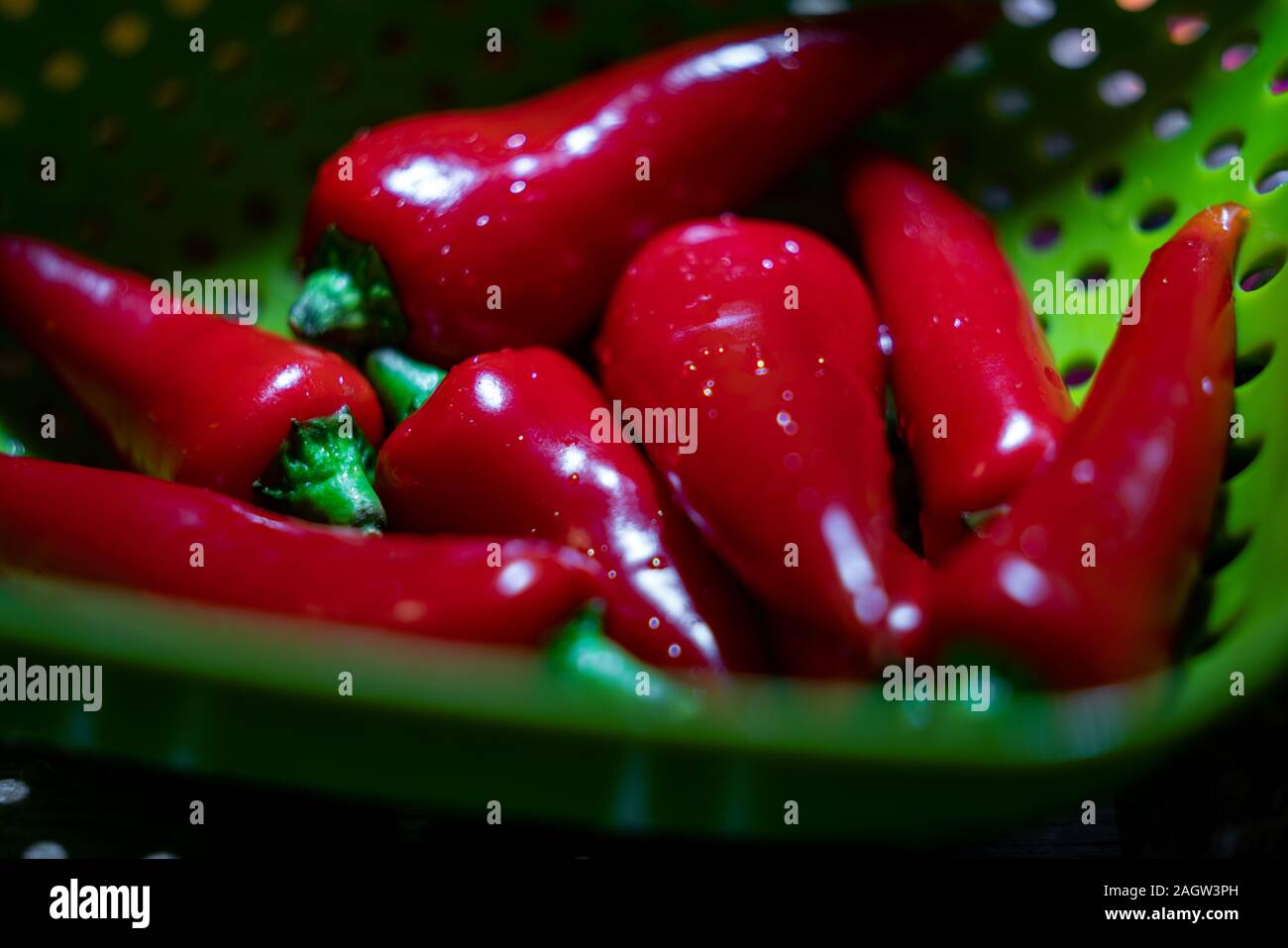 Freshly washed red spicy chilli in a green drainer ready to cook Stock Photo