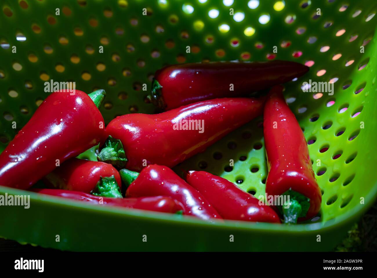Freshly washed red spicy chilli in a green drainer ready to cook Stock Photo