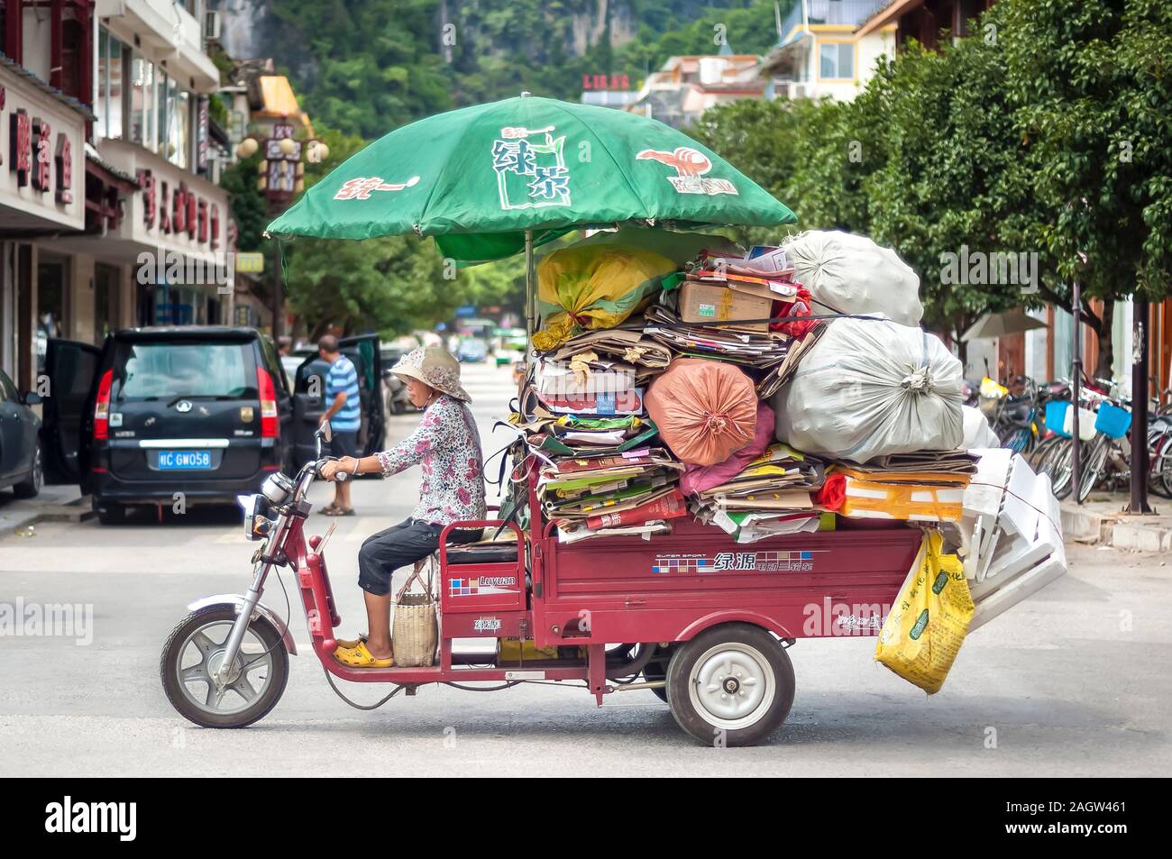 YANGSHUO, CHINA - AUG 10, 2013 - Small truck overloaded with cardboard and bags of plastic bottles in the Southwestern town of Yangshuo, China Stock Photo
