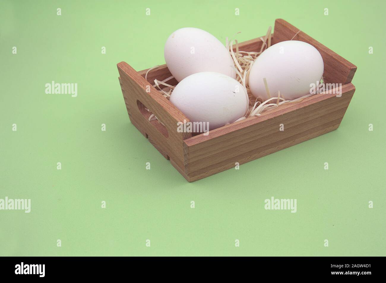 A box with three white eggs on a neutral green background Stock Photo