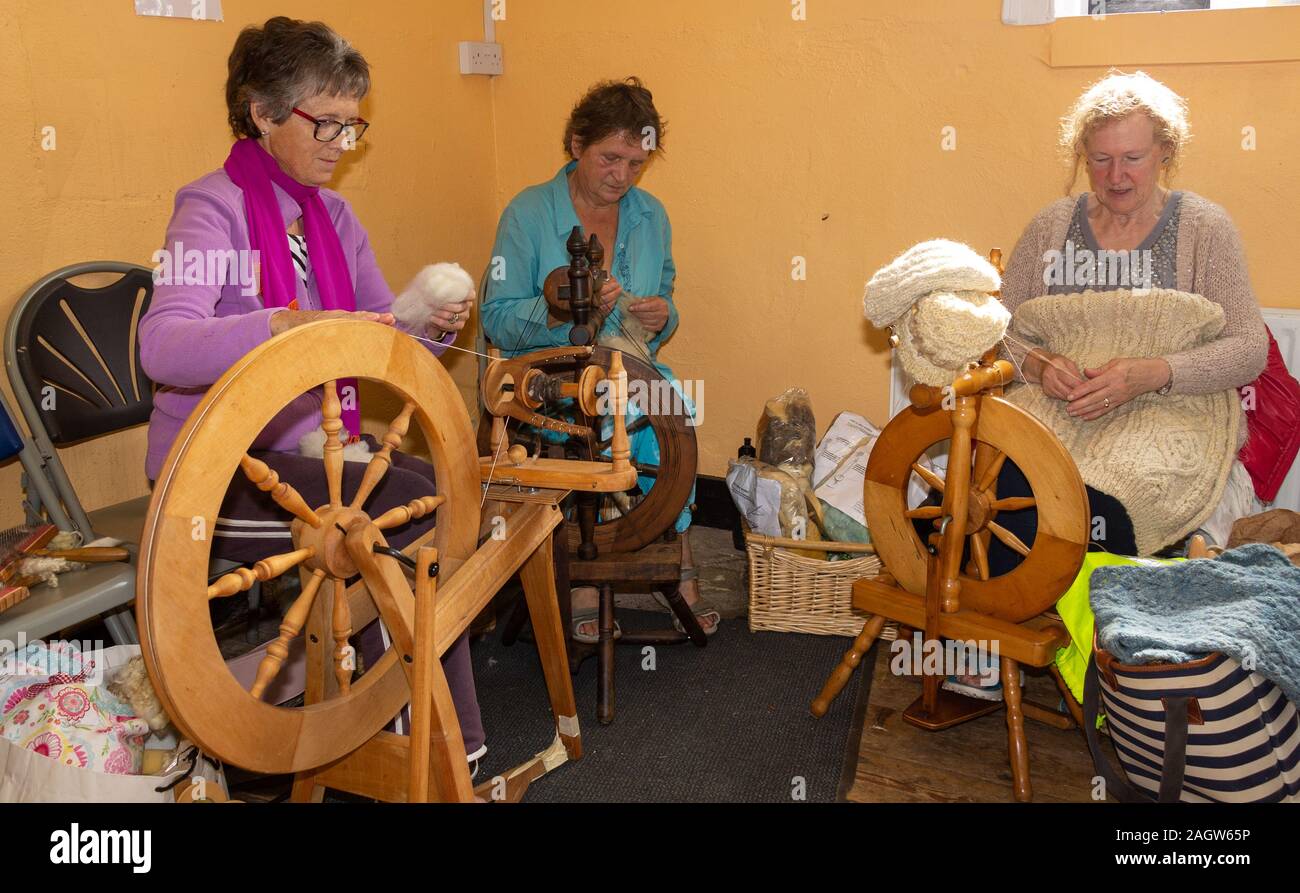 3 mature ladies spinning wool on pedal spinning wheels. Stock Photo