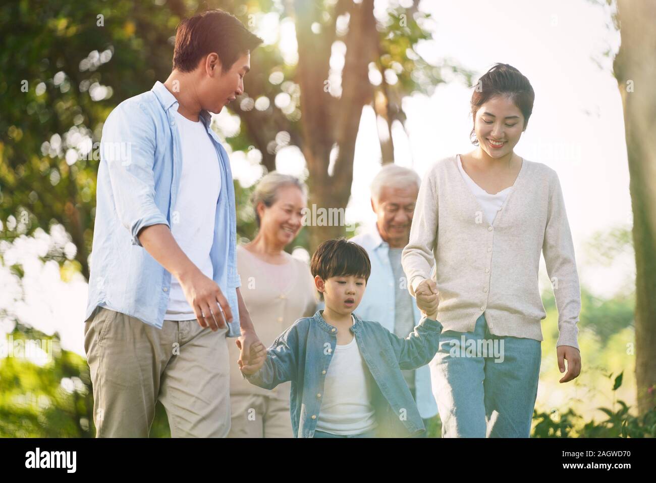 three generation happy asian family walking outdoors in park Stock Photo
