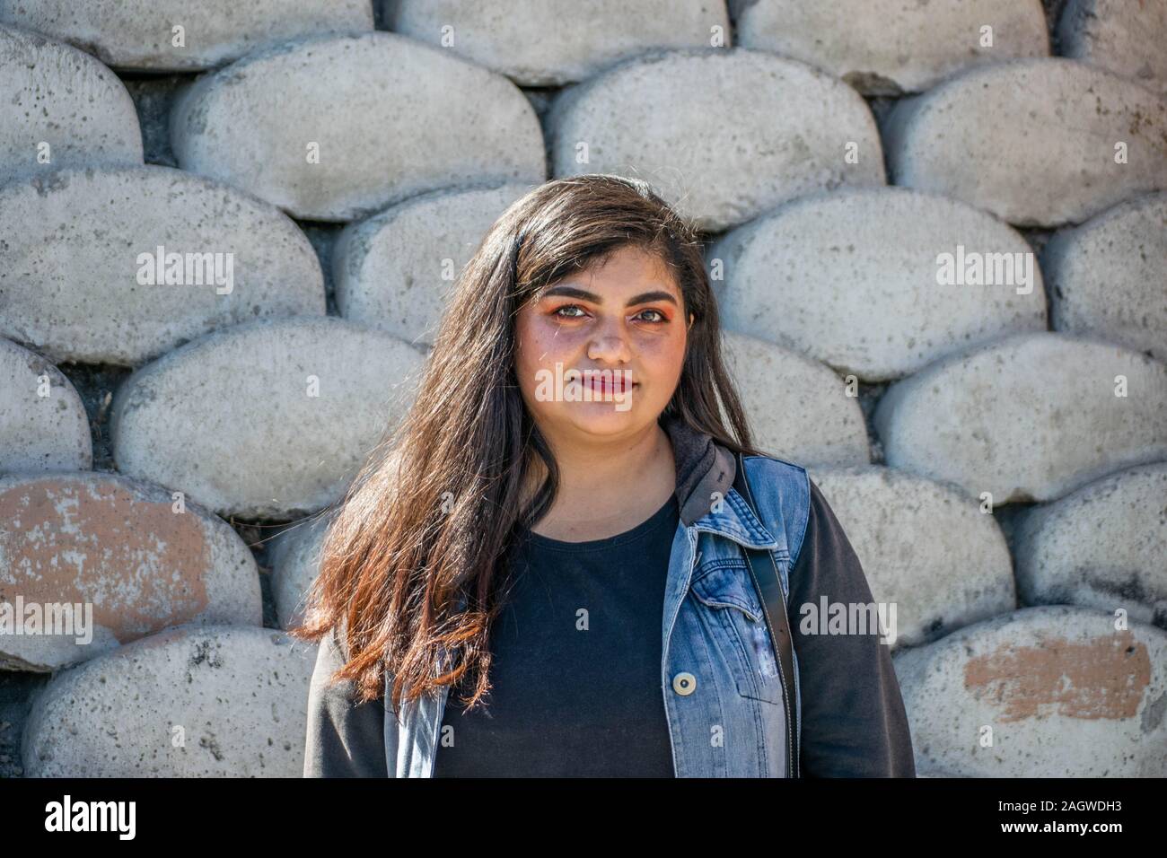 chubby woman with latin or hindu appearance in front of concrete wall Stock Photo