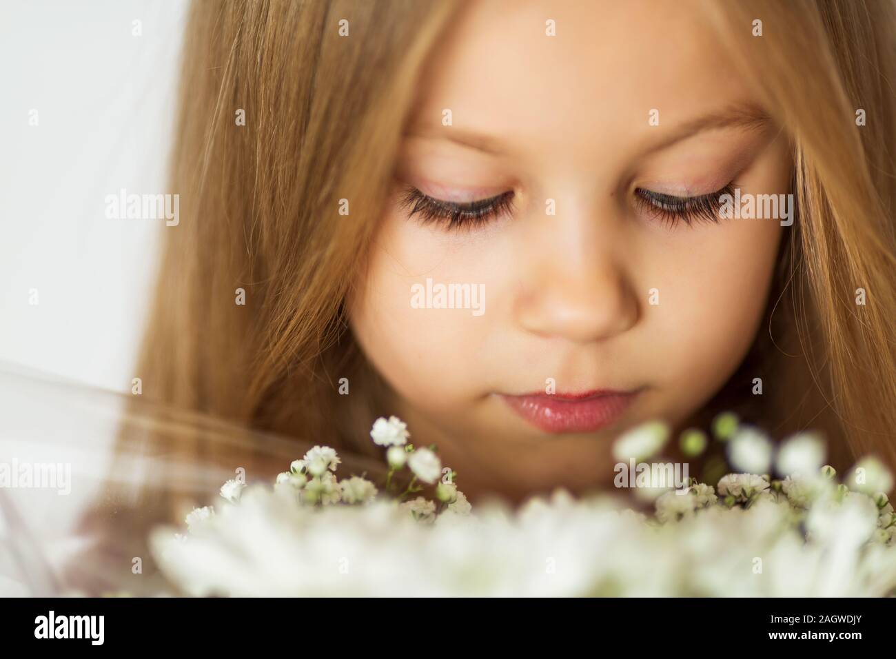 close up beautiful little blond girl with a bouquet of wildflowers with weathered lips Stock Photo