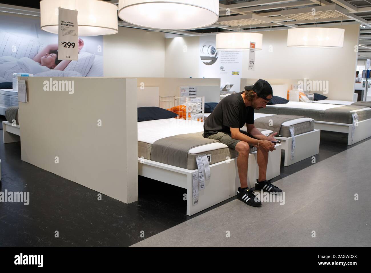 New Haven, CT USA. Sep 2018. Man sitting on display bed surfing on smartphone at world famous IKEA home furnishings outlet. Stock Photo