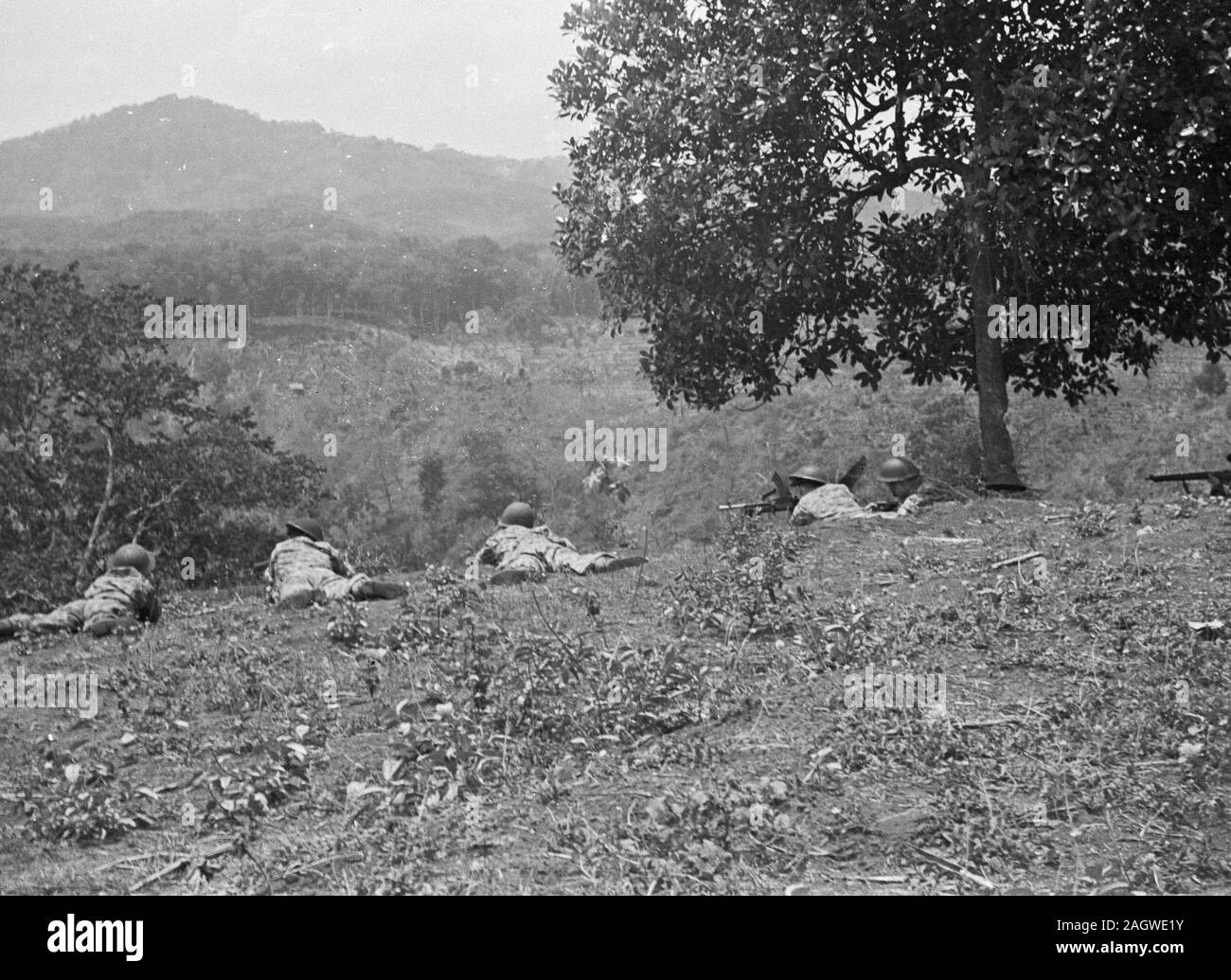 Soldiers lie on the ground in position and overlook a valley in Bandung, Indonesia, Dutch East Indies ca. 1946 Stock Photo