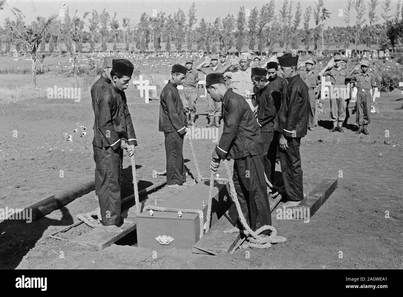 Cemetery workers lowing a coffin into a grave in Indonesia ca. 1947 Stock Photo