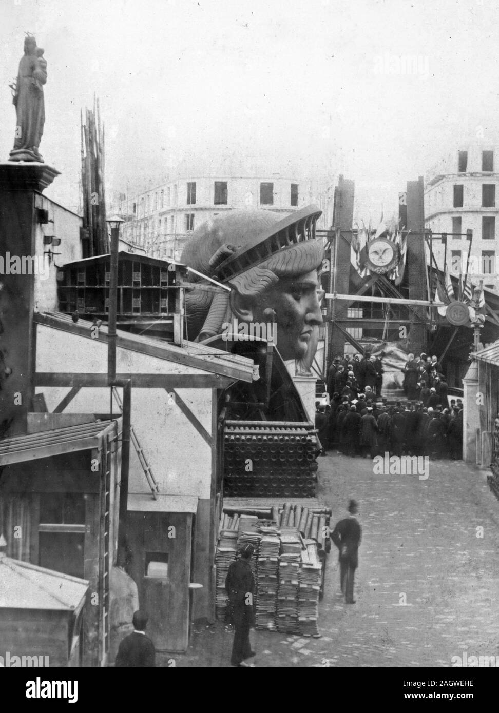 External area of the workshop in Paris, showing construction materials, the head of the Statue of Liberty, and a group of men Stock Photo