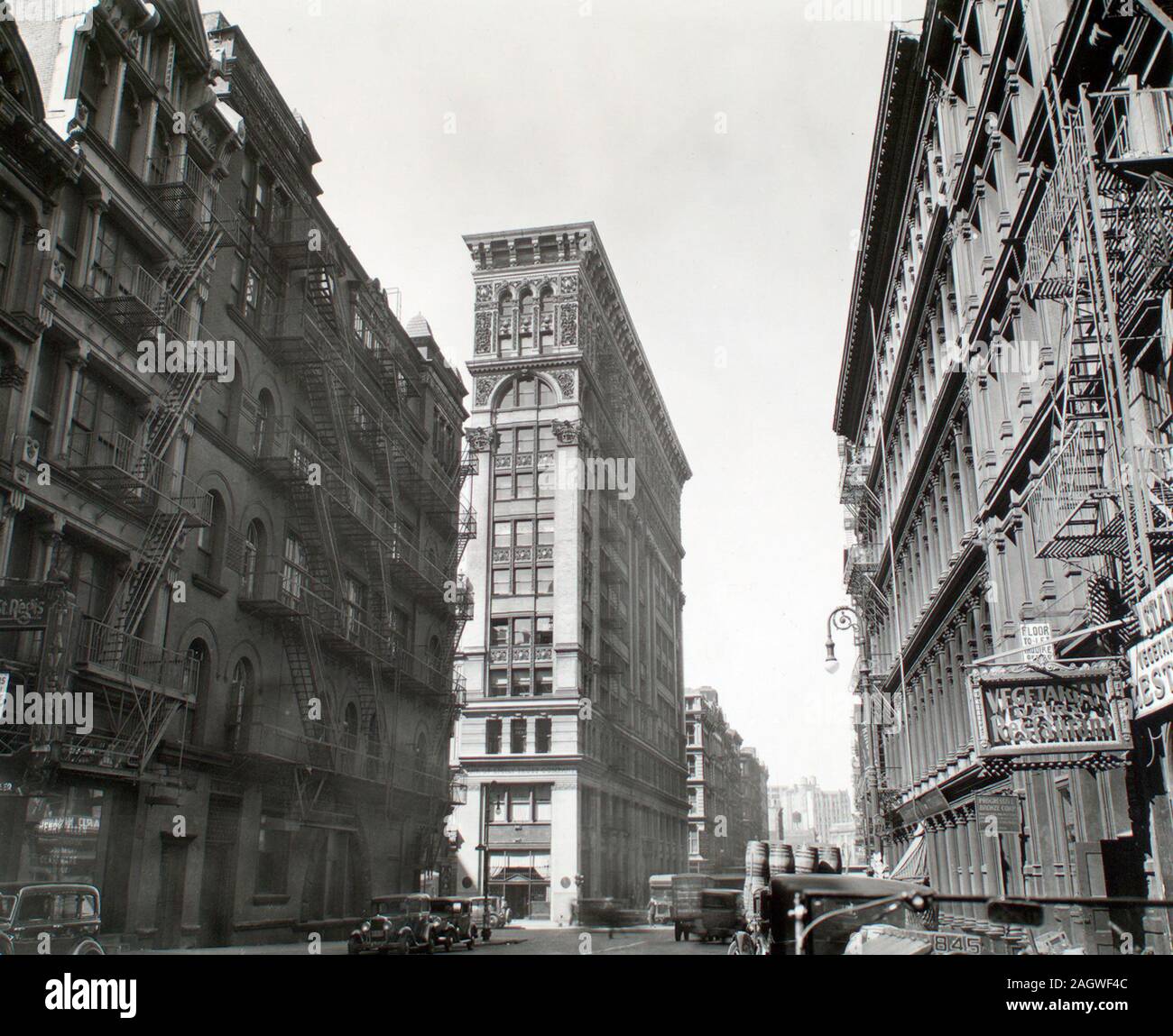 1930s New York City - Looking down Broadway, ornate Bank of Sicily Trust near center of image, sign for vegetarian restaurant, right, cars and trucks, Broadway near Broome Street, Manhattan ca. 1935 Stock Photo
