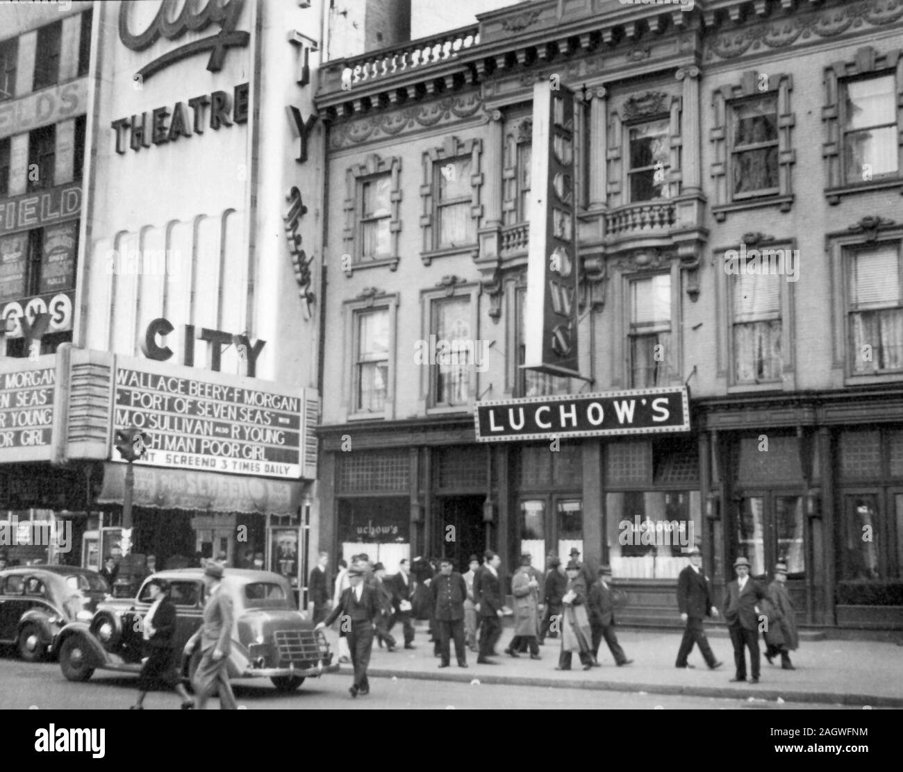 Pedestrians fill walk in front of Luchow's Restaurant, the City Theater next door features Wallace Beery and Margaret O'Sullivan films. Stock Photo