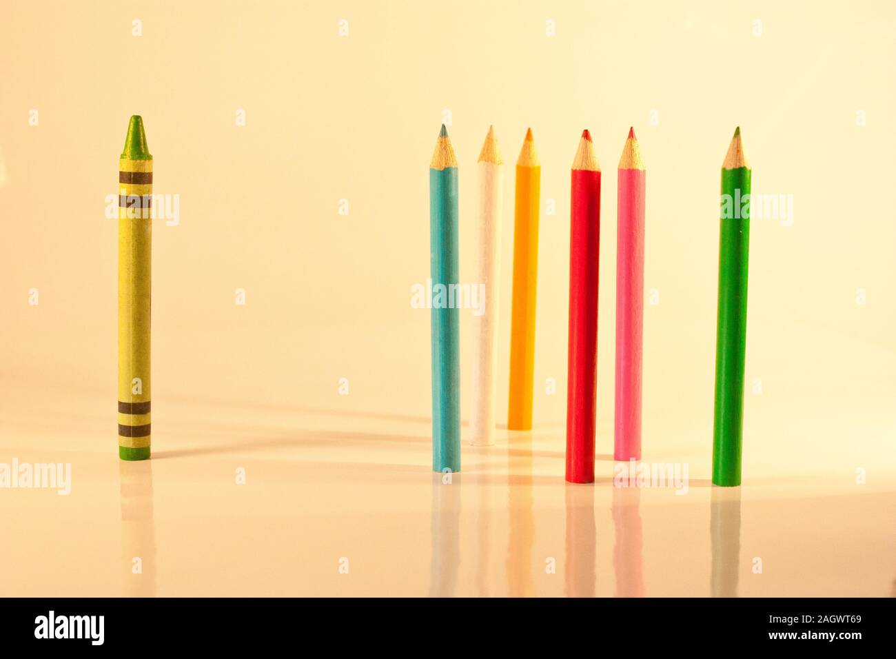 A concept of victimisation with a single coloured crayon standing apart from coloured pencils. Stock Photo