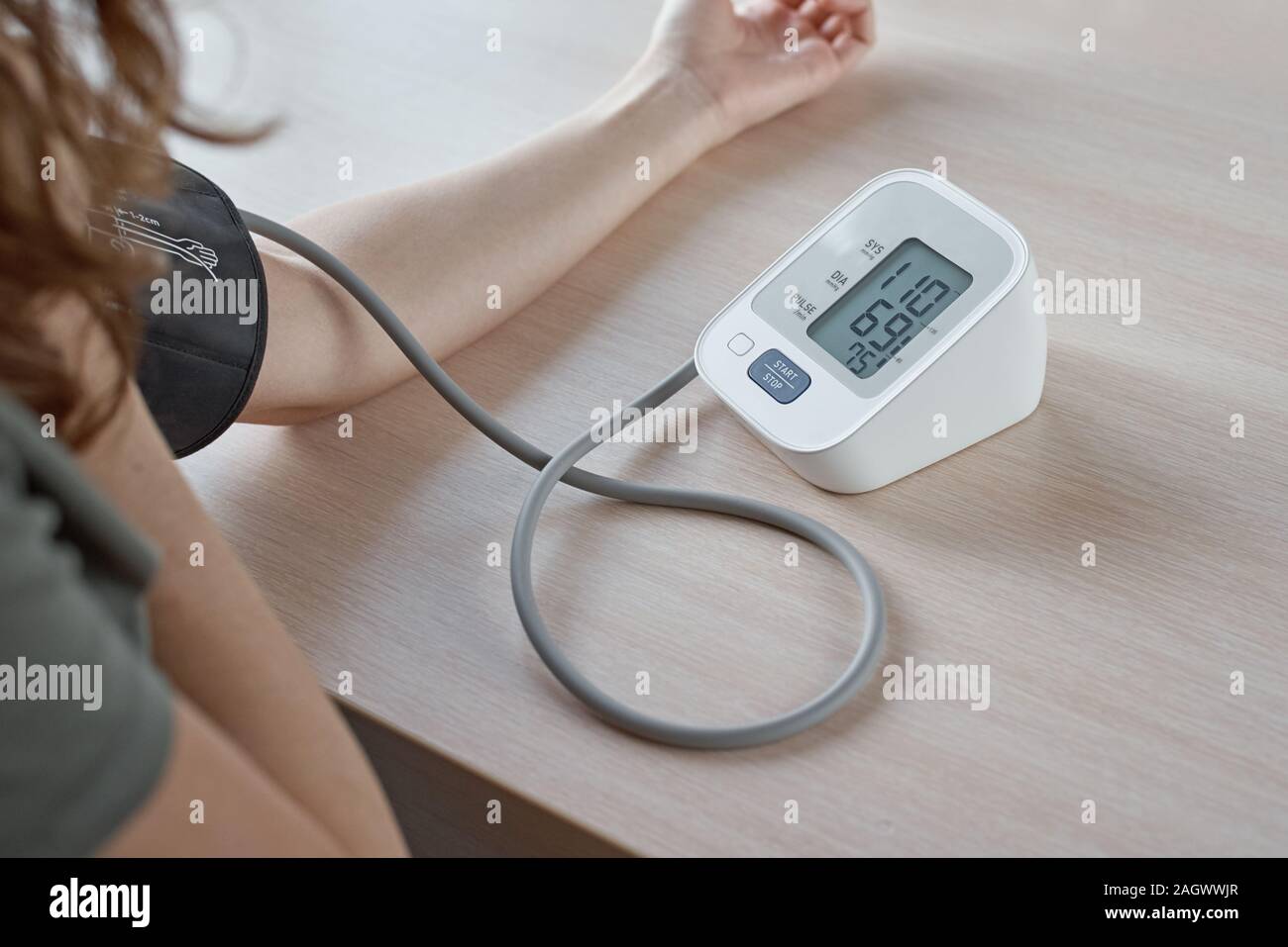 Woman measuring blood pressure with electric digital tonometer