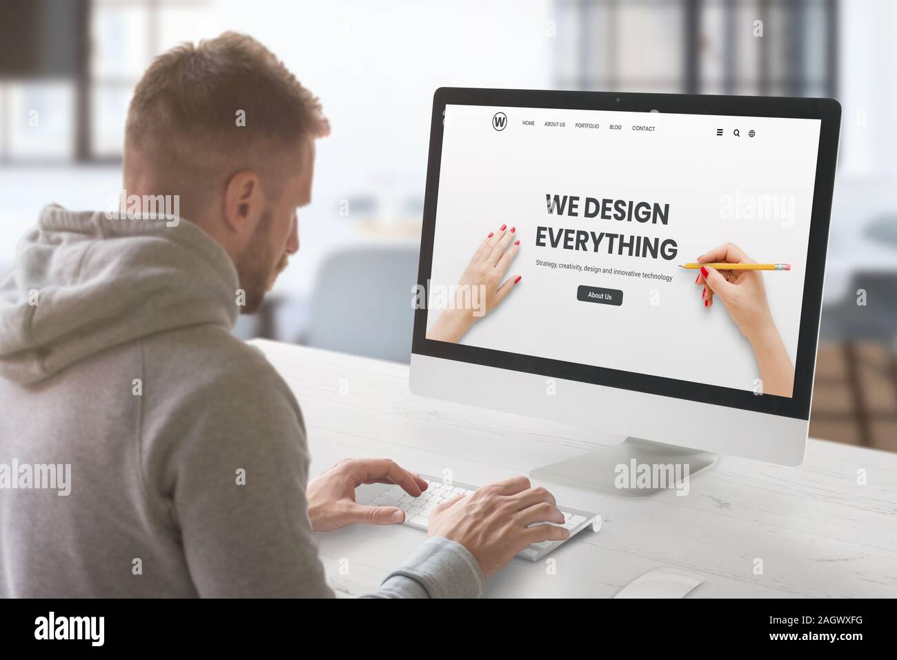 Web design studio with concept agency web page on computer display. Guy work on computer. Office interior Stock Photo