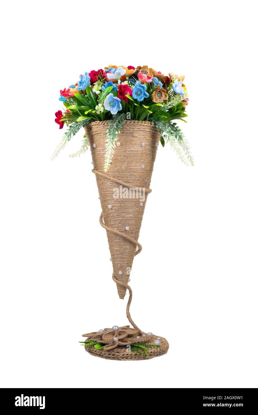 Decorative knitted flowers in a conical vase on a white background isolated. Handwork, hobby. Stock Photo