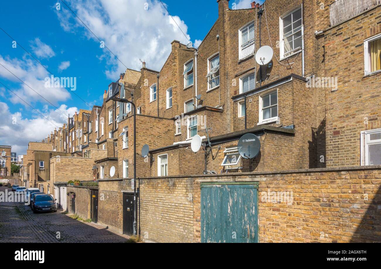 Typical rear view of multi storey, brick built, period terraced properties, with back yards and an access lane. Acton, West London, W3, England, UK. Stock Photo