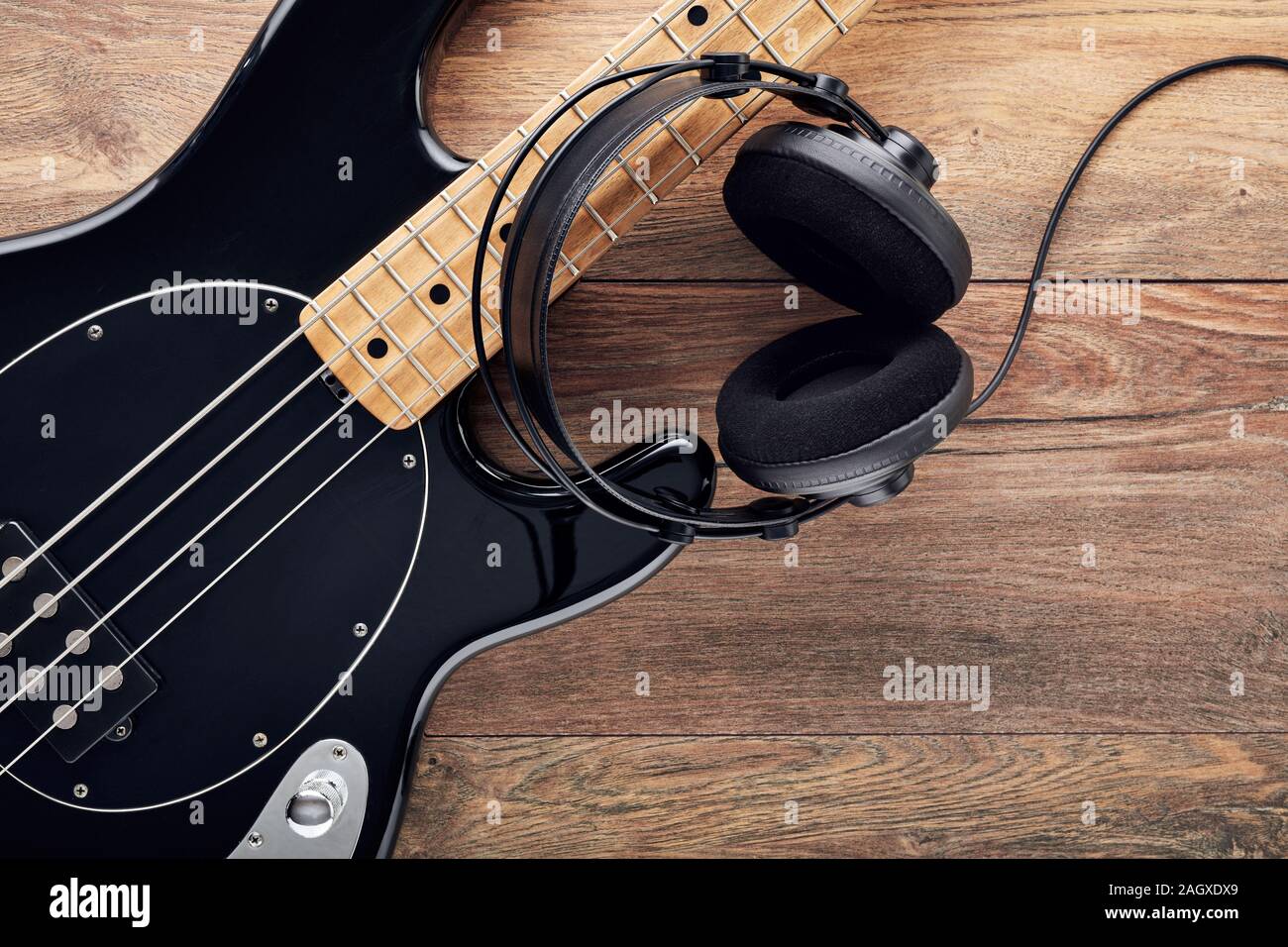 Black bass guitar with headphones on wooden table Stock Photo Alamy