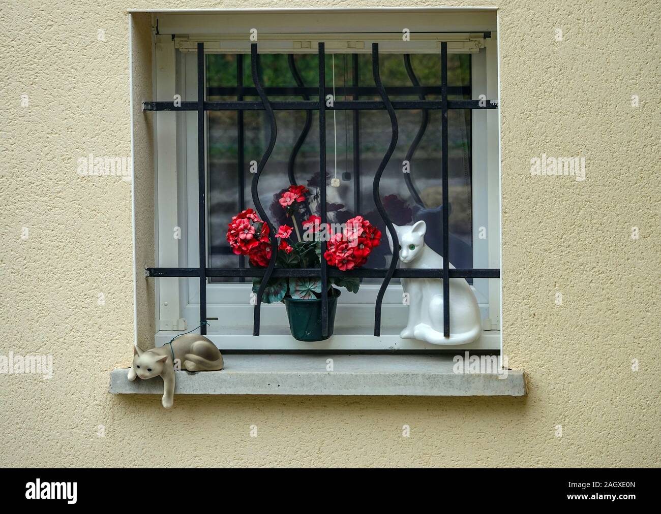 Porcelain cat and kitten with red flowers on window ledge, Verdun, Les Cabannes, Tarascon sur Ariege, France Stock Photo