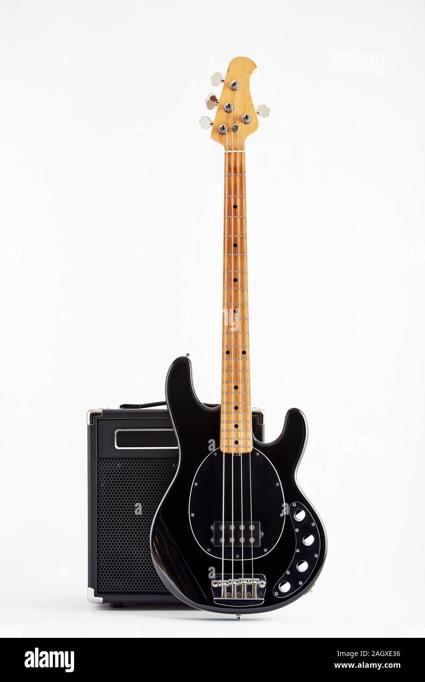 Vintage black electric bass guitar and amplifier on white background
